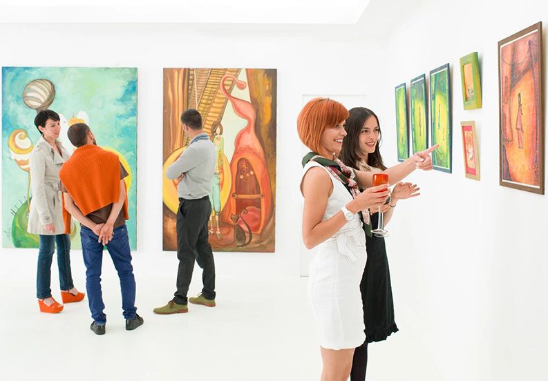 A group of people standing in front of paintings.