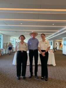 Three people standing in a conference room.