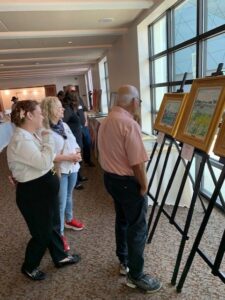People viewing paintings in a gallery exhibit.