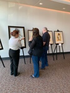 People viewing framed artwork in gallery.