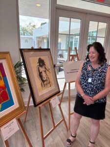 Woman standing beside displayed artwork in gallery.