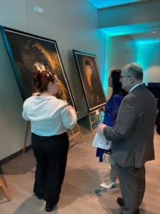 People viewing paintings at an art exhibit.