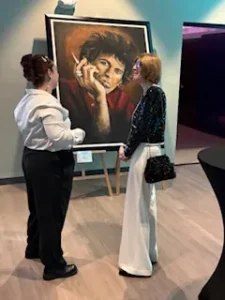 Two women admiring a portrait painting.