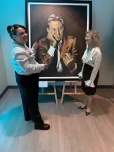 Two women discussing a large framed painting.